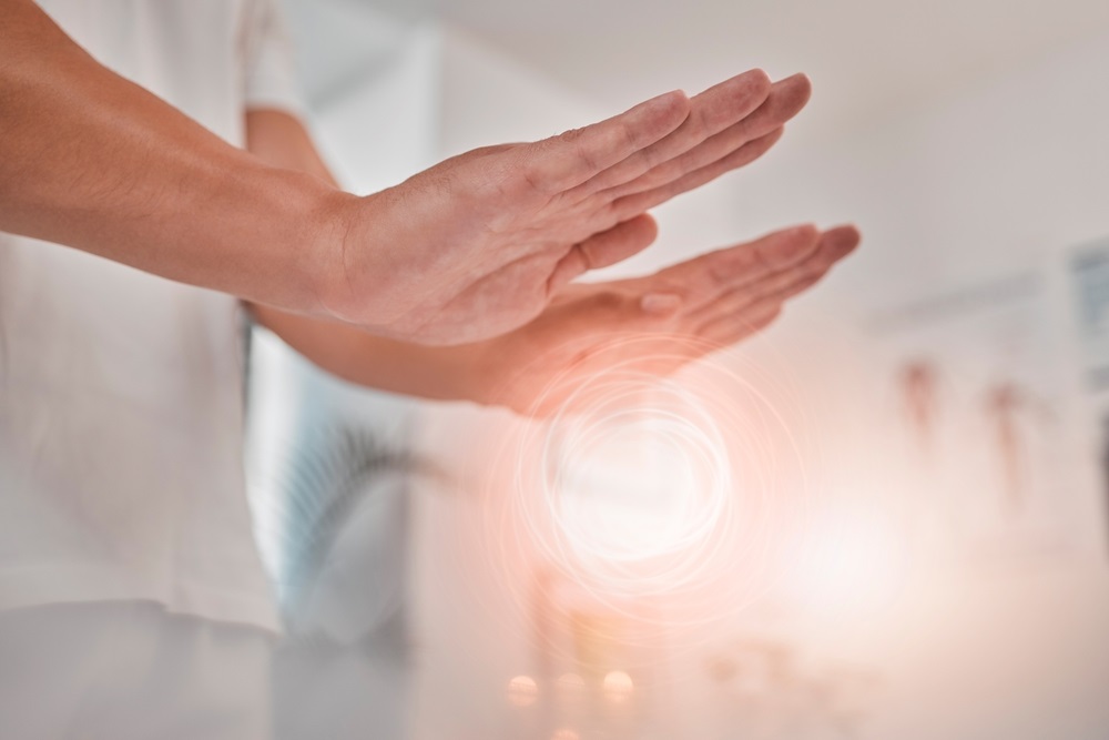 Person practicing energy healing exercises with radiant energy flow in a peaceful environment.