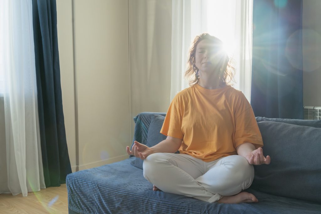 Woman meditating indoors in a peaceful and calm setting to release emotional tension